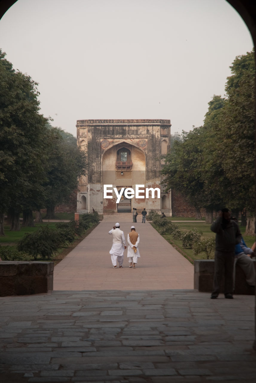 People walking on pathway against built structure