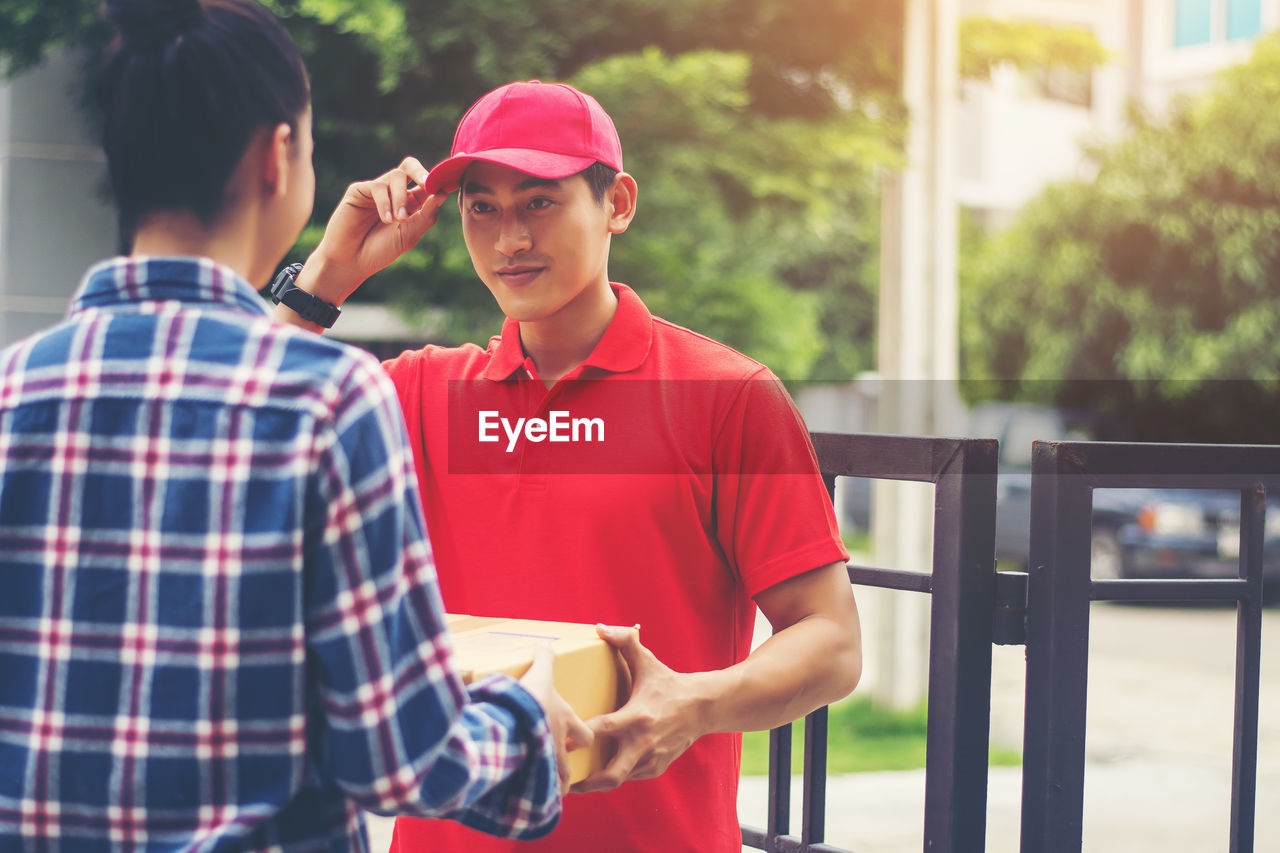 Man delivering package to female customer at gate