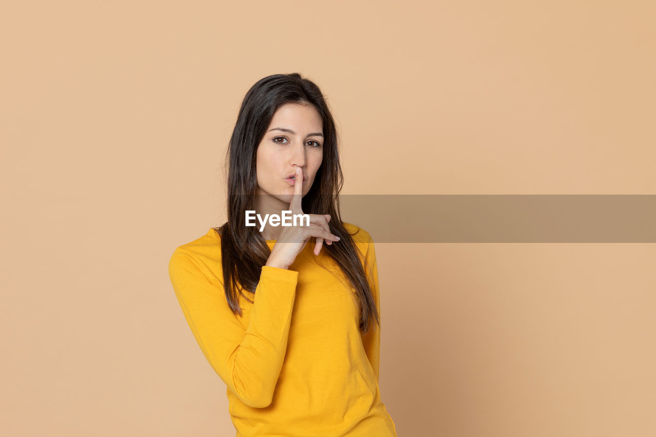 PORTRAIT OF BEAUTIFUL YOUNG WOMAN AGAINST GRAY BACKGROUND