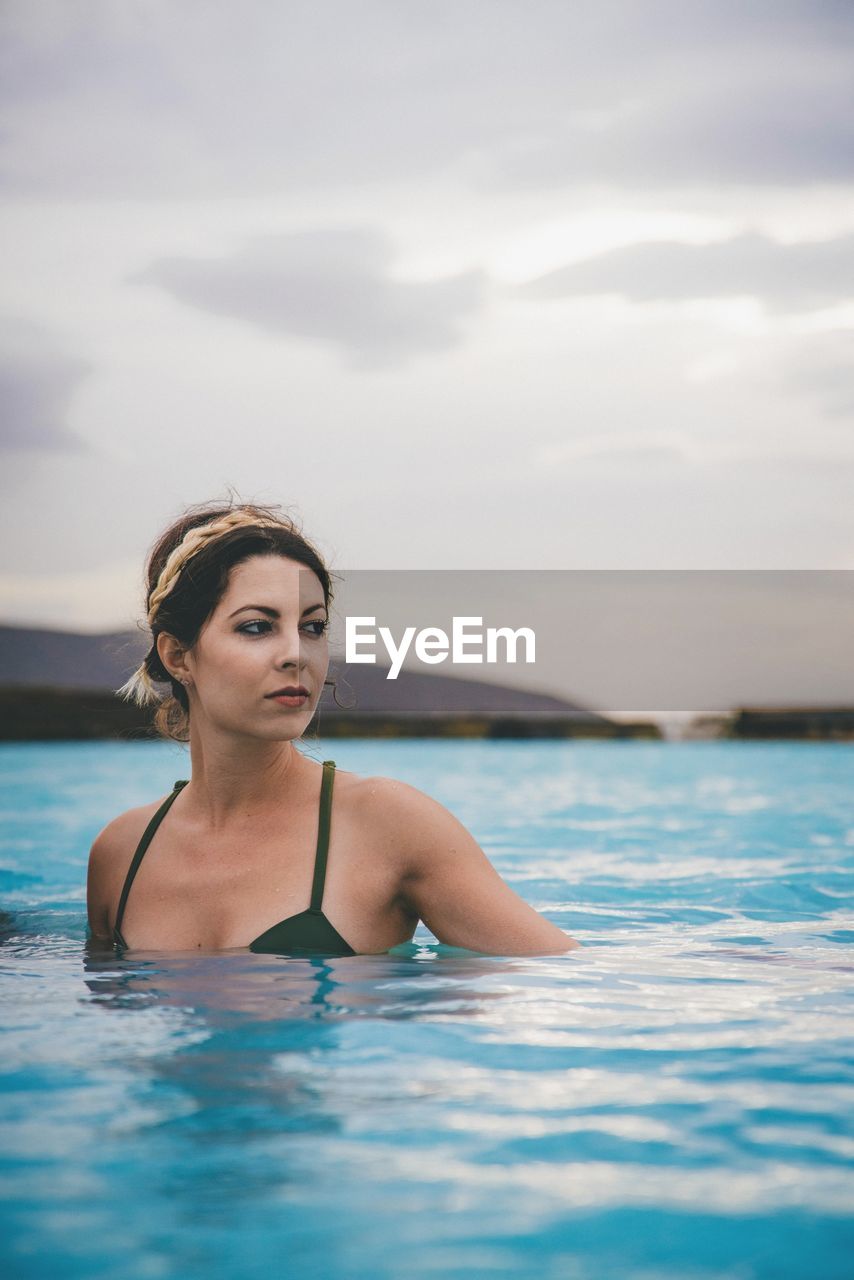 Woman in swimming pool against sea