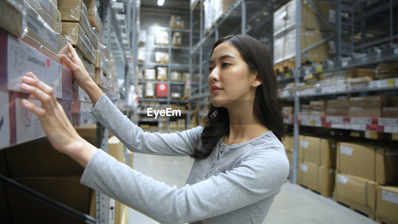 YOUNG WOMAN LOOKING AWAY WHILE STANDING ON DISPLAY AT STORE