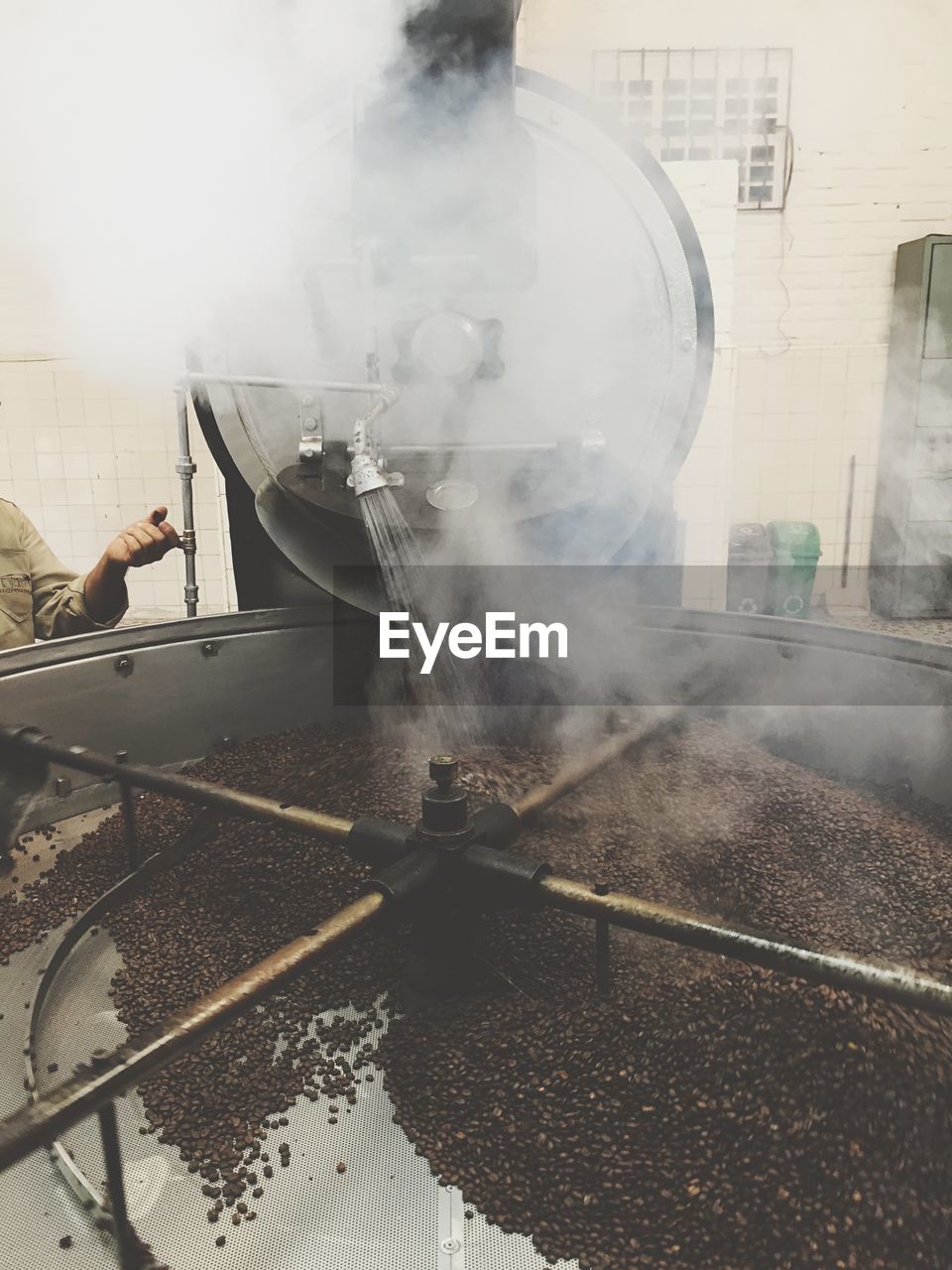 Cropped image of worker cleaning coffee crops in factory container