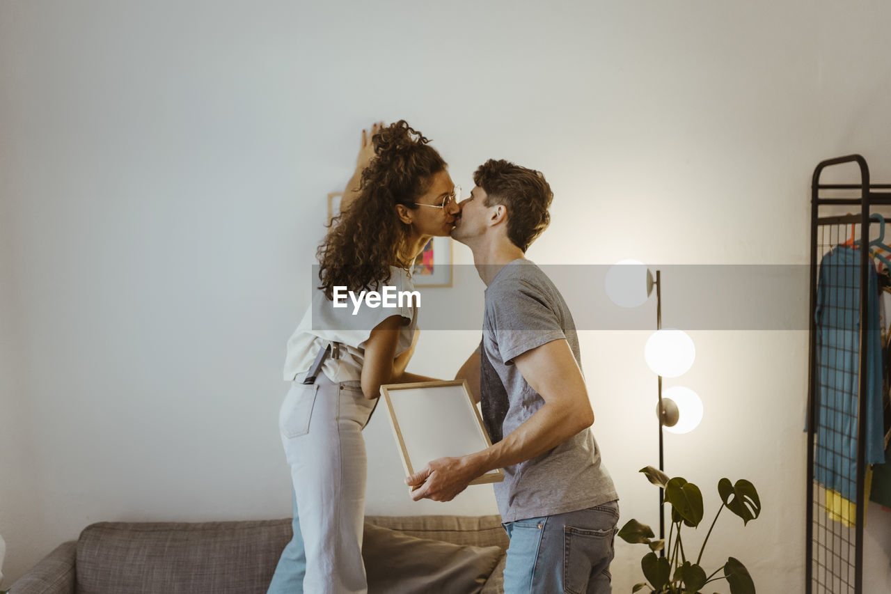 Side view of couple kissing each other against wall at home