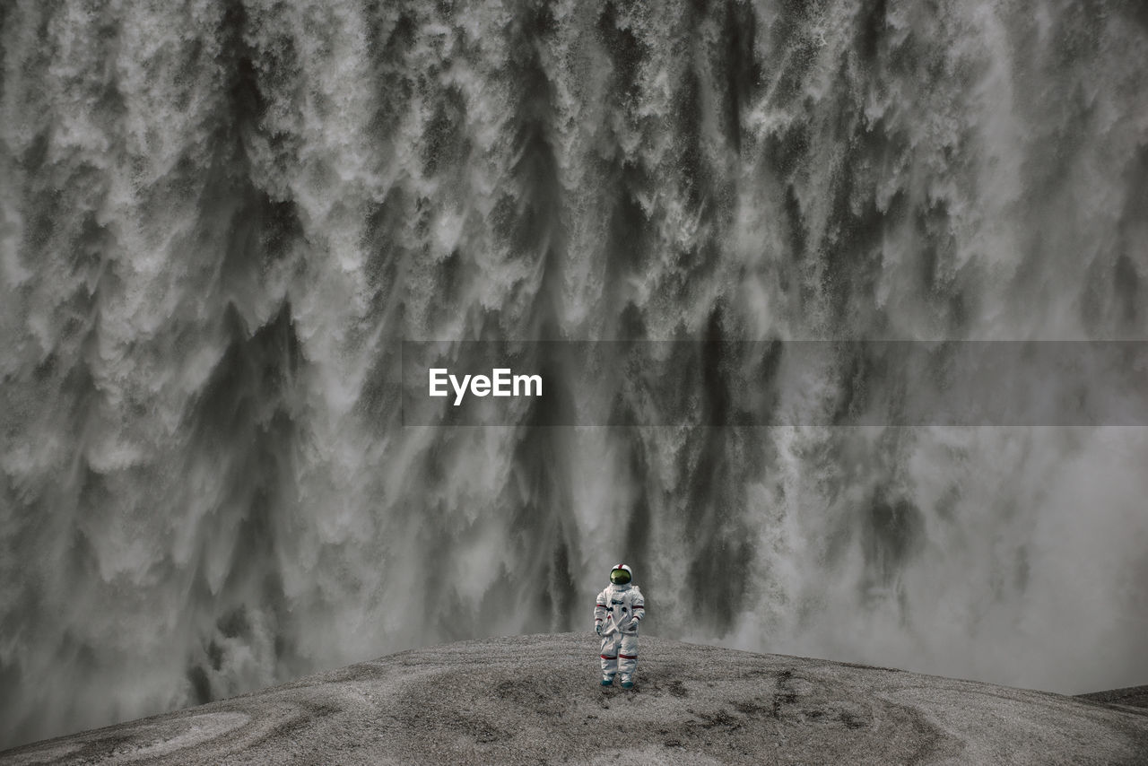 Full length of astronaut standing by waterfall