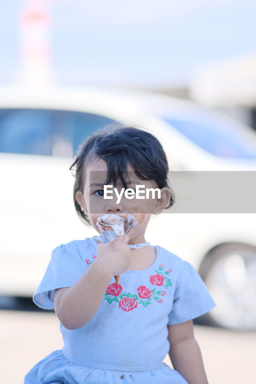 Portrait of cute girl eating ice cream outdoors