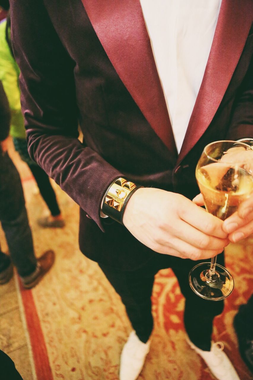 Close-up mid section of man holding wine glass