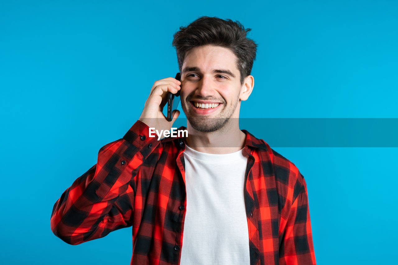 PORTRAIT OF A YOUNG MAN AGAINST BLUE BACKGROUND