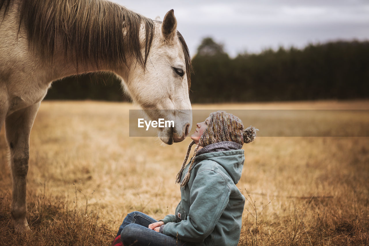 Horse and girl looking at each other in field in the fall