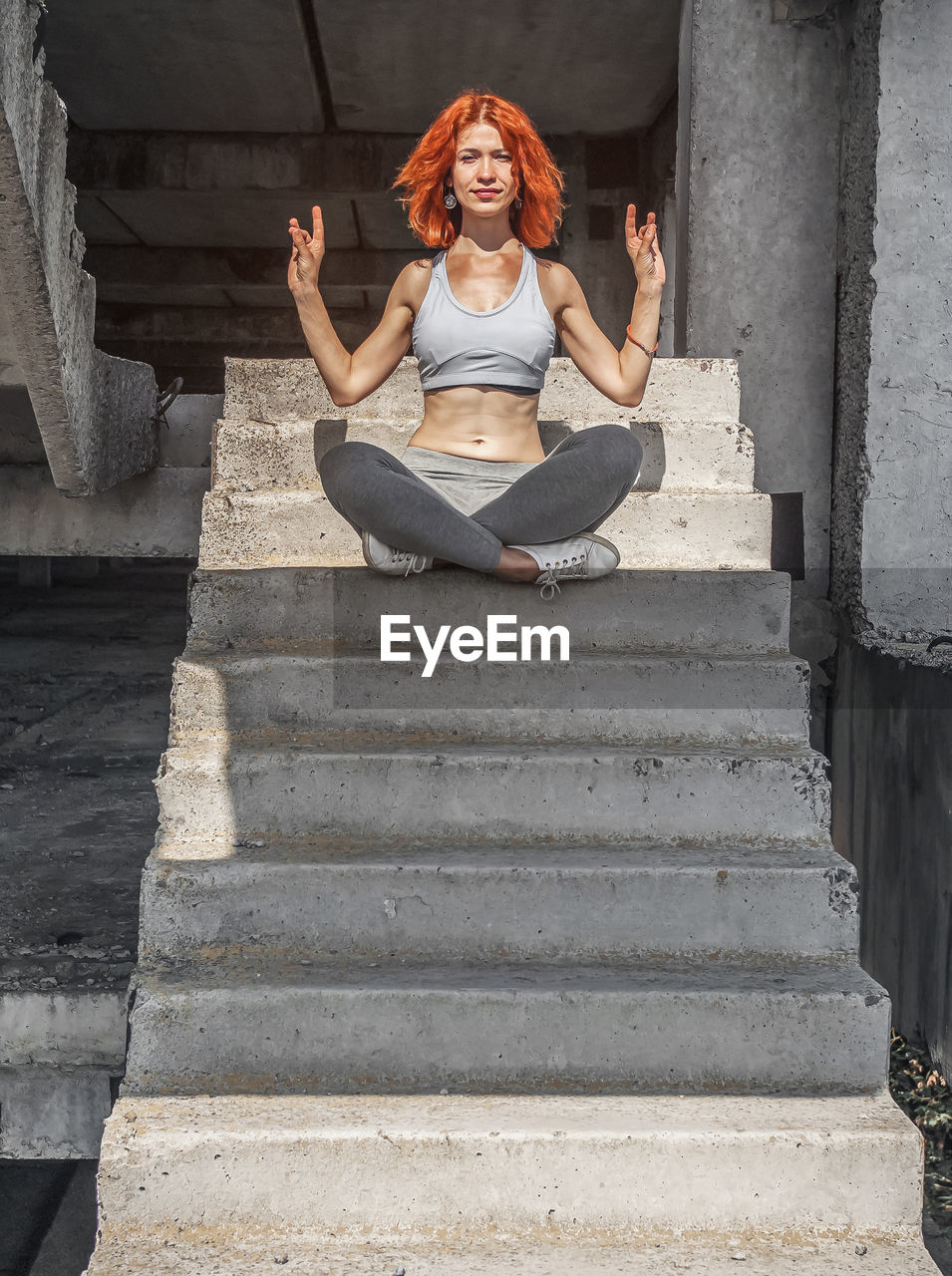 Cheerful woman, relaxing after fitness workout in park, sitting on concrete steps outdoors