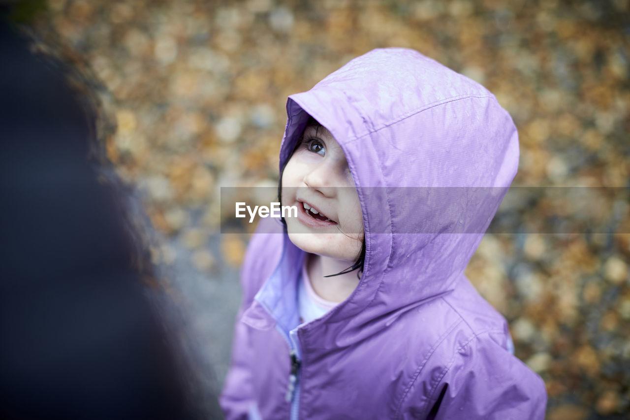 A happy portrait of a little girl outdoors in the rain.
