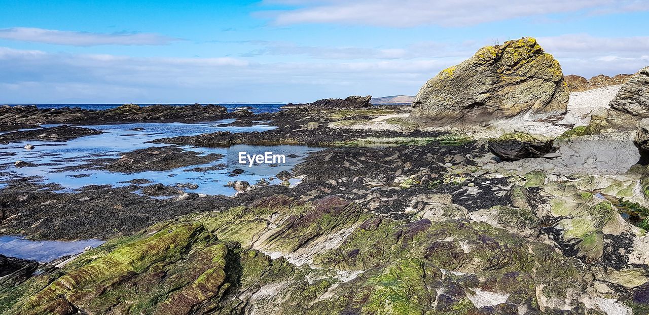 SCENIC VIEW OF ROCKS ON BEACH AGAINST SKY