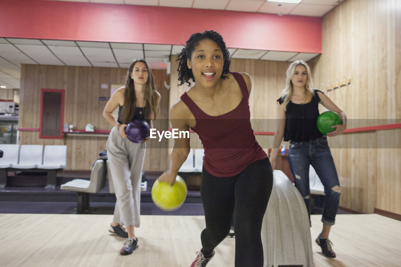 A young woman bowling with friends.