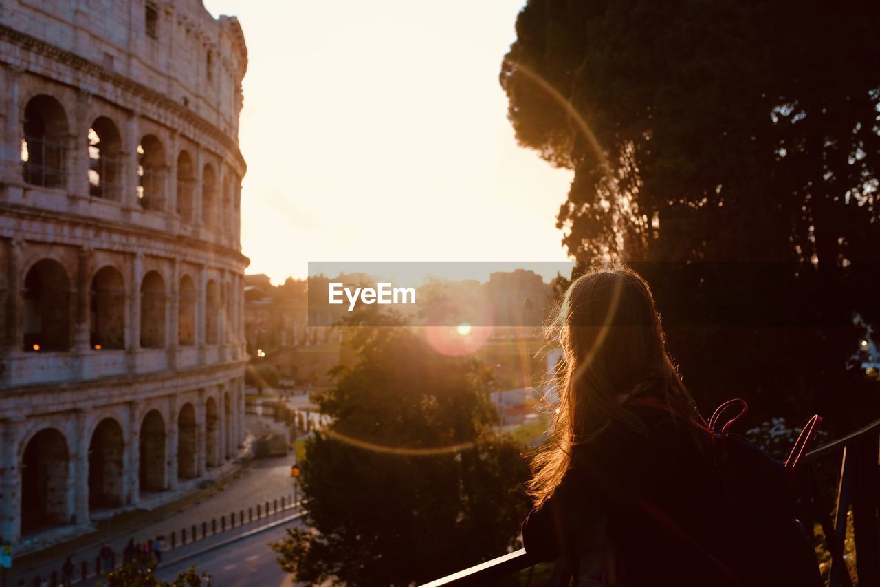 Rear view of woman in city at sunset