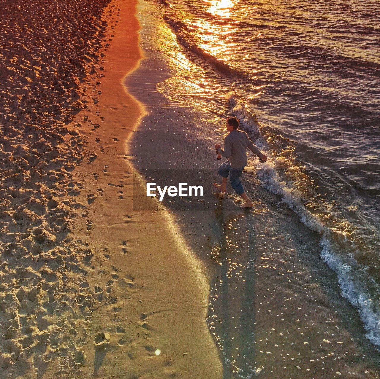 High angle view of man walking at beach during sunset