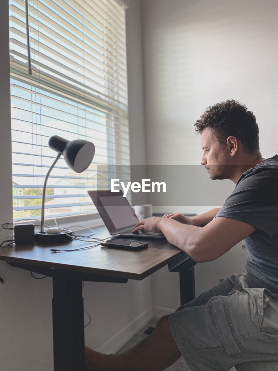 Side view of man working by using laptop at home