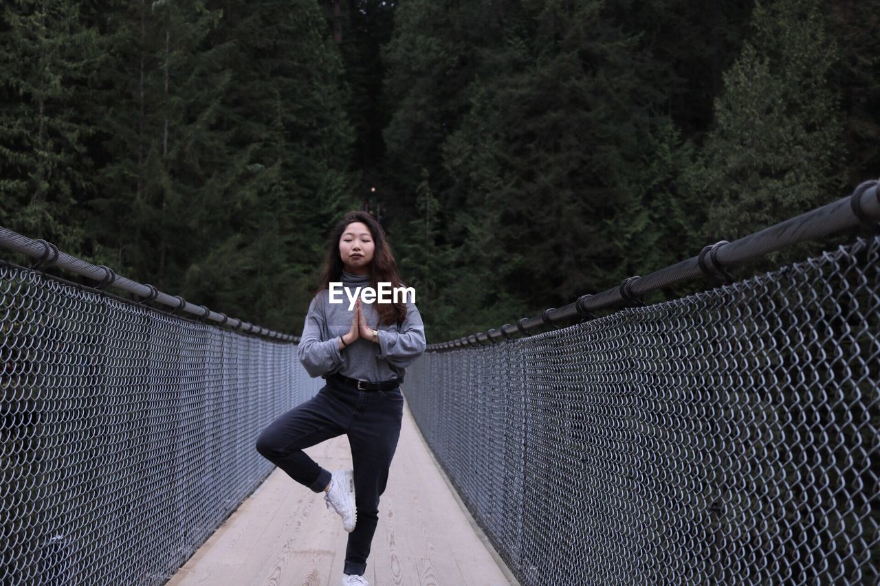 Young woman in tree pose on capilano suspension bridge against mountain