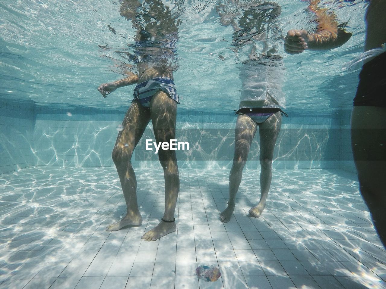 Underwater low section of women standing in pool 