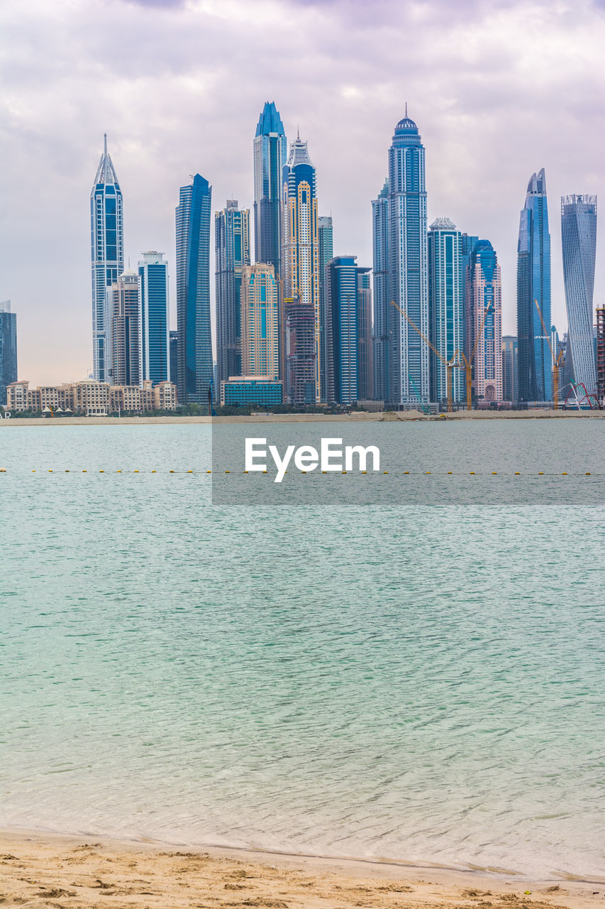 SEA AND BUILDINGS AGAINST SKY IN CITY