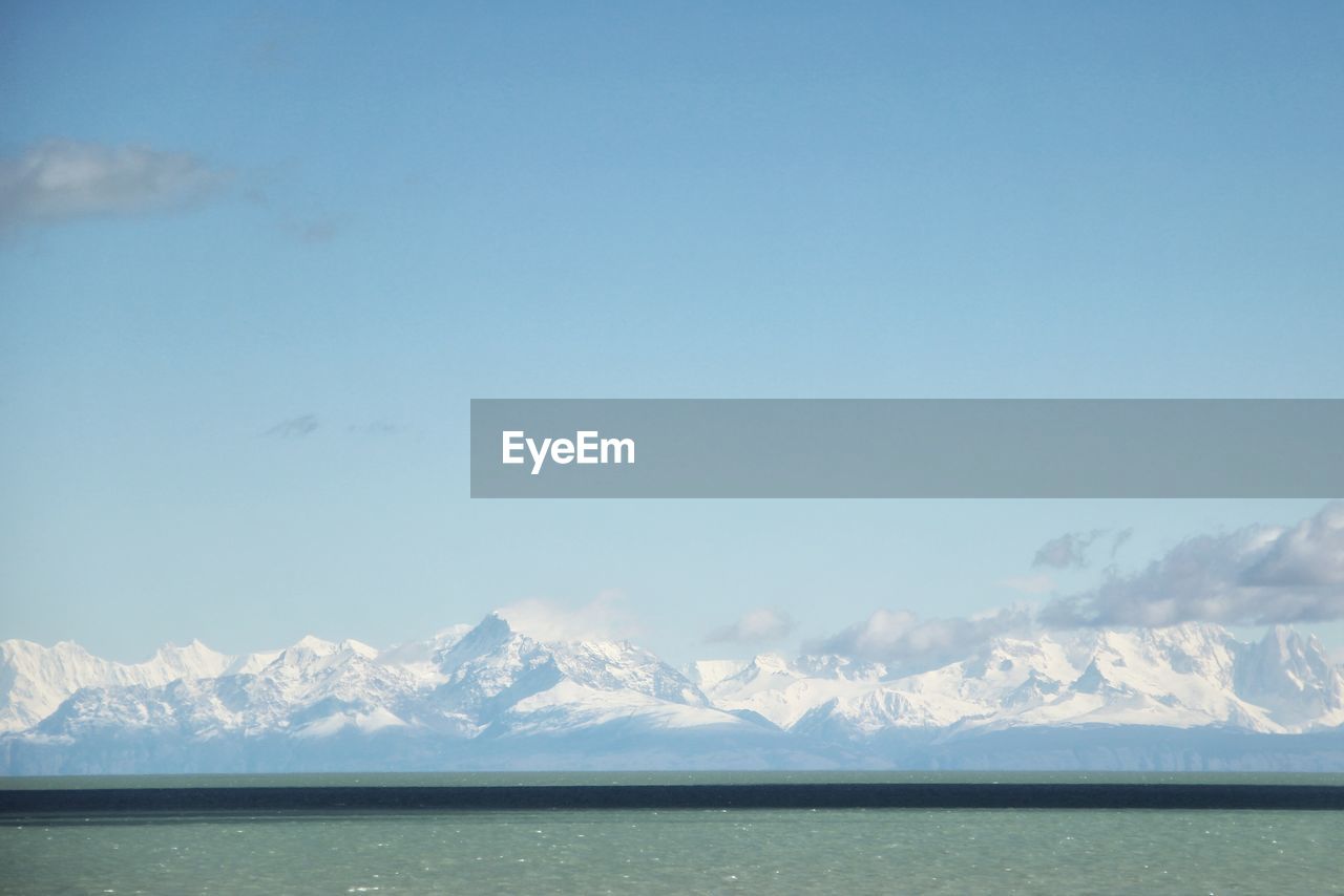 Scenic view of sea and snowcapped mountains against sky