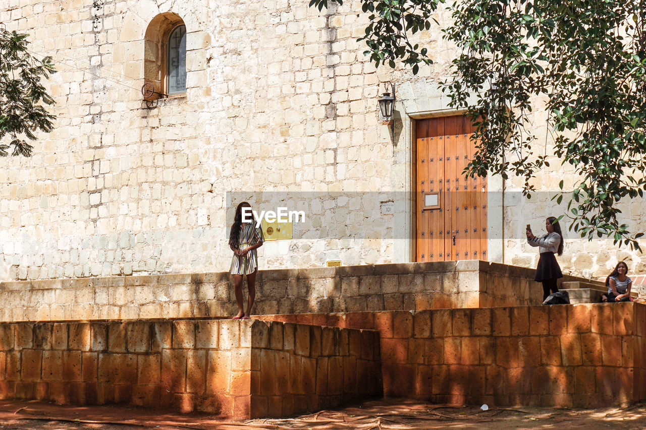 WOMAN ON WALL AGAINST BUILDING