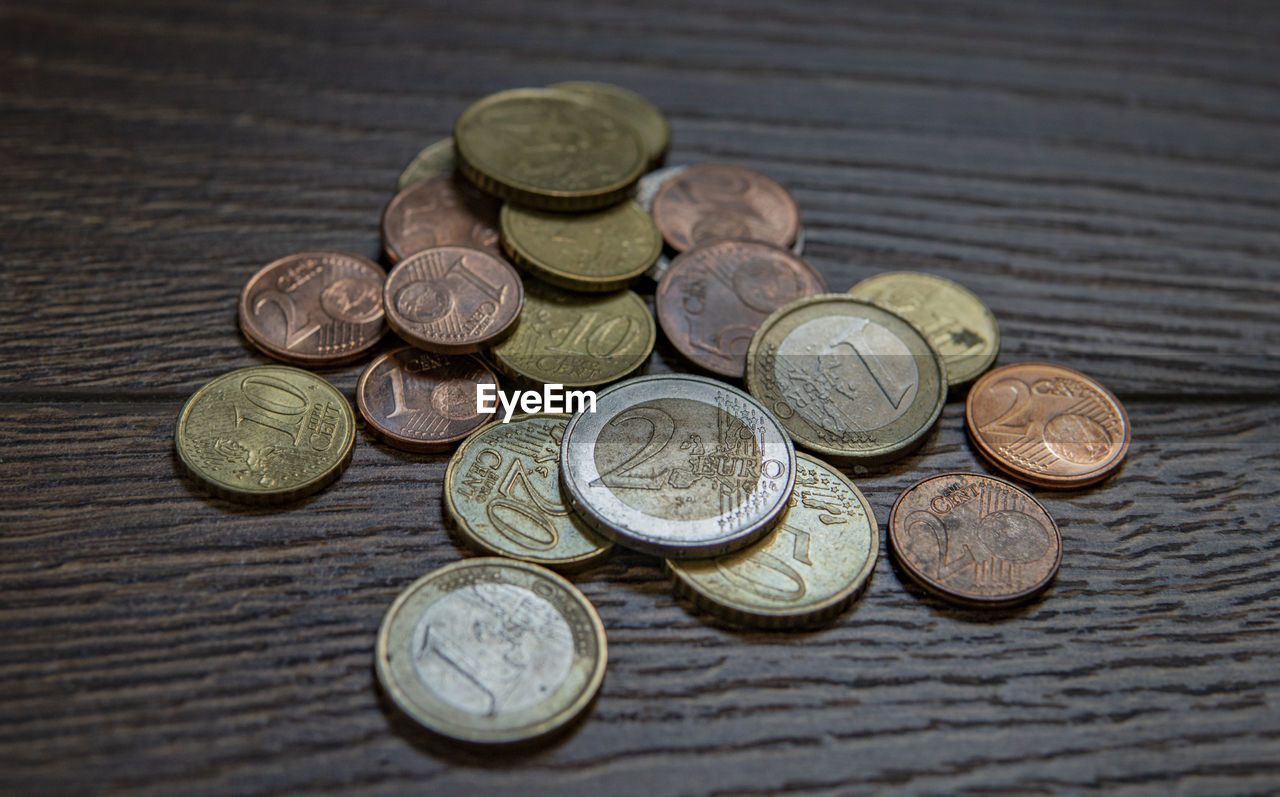 HIGH ANGLE VIEW OF COINS IN CONTAINER ON TABLE