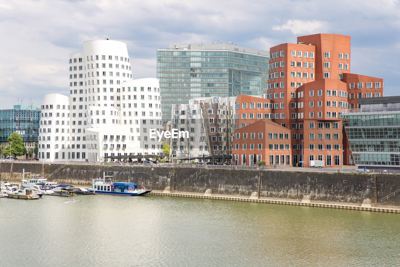 BUILDINGS BY RIVER AGAINST SKY