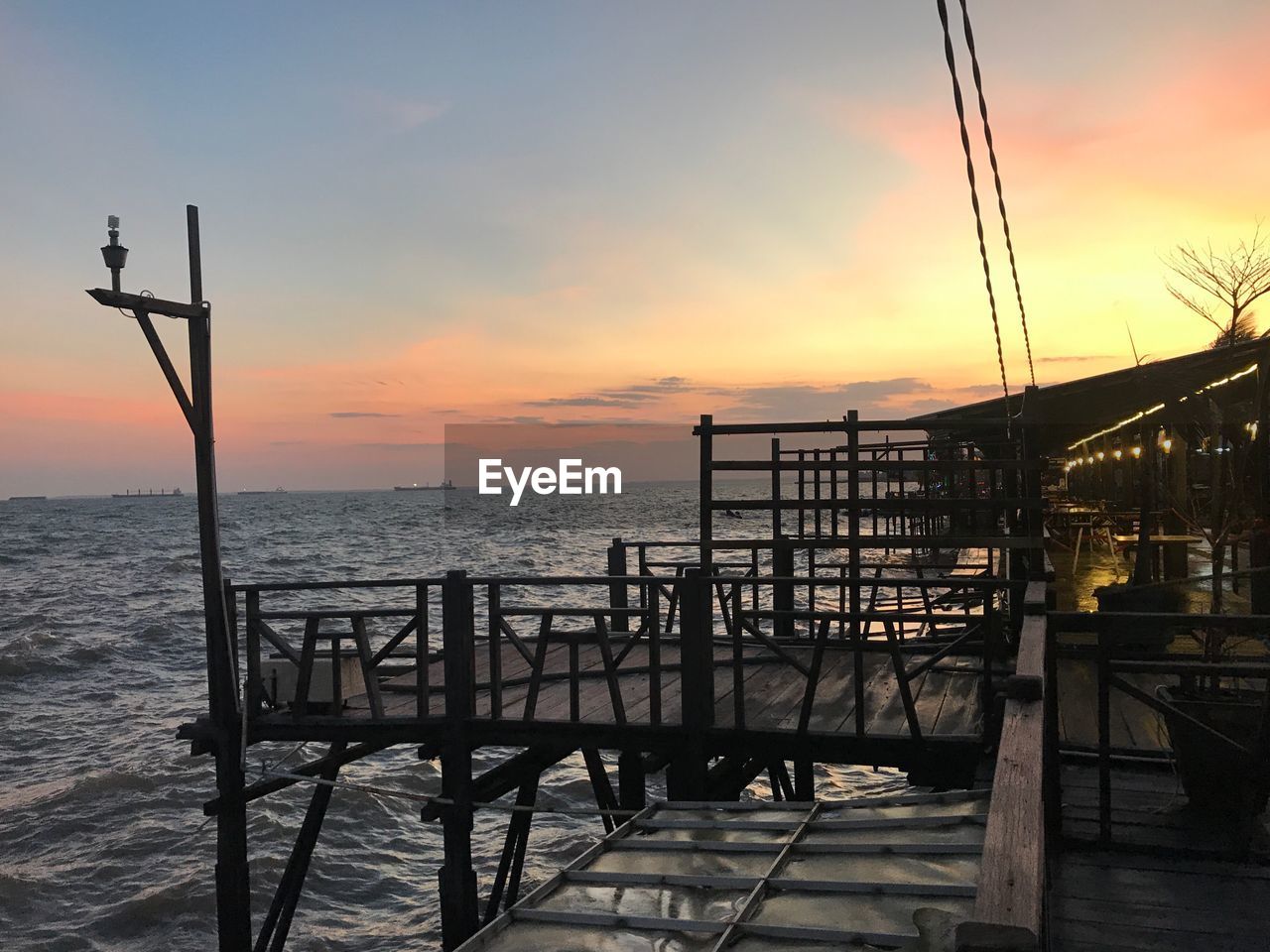 Pier on sea against sky during sunset