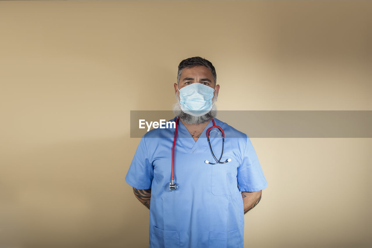 Portrait of a male nurse in blue gown and mask on a light background person