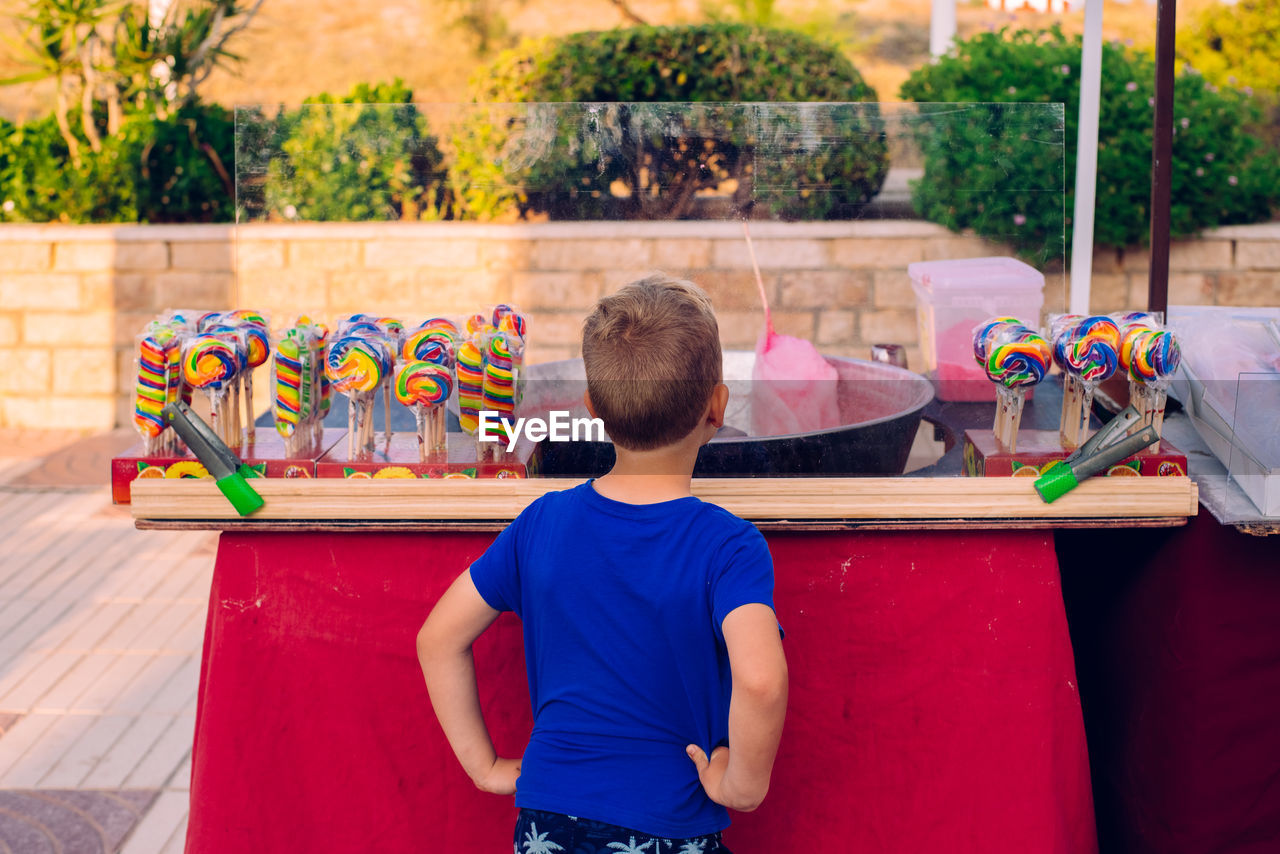 Rear view of boy standing at store