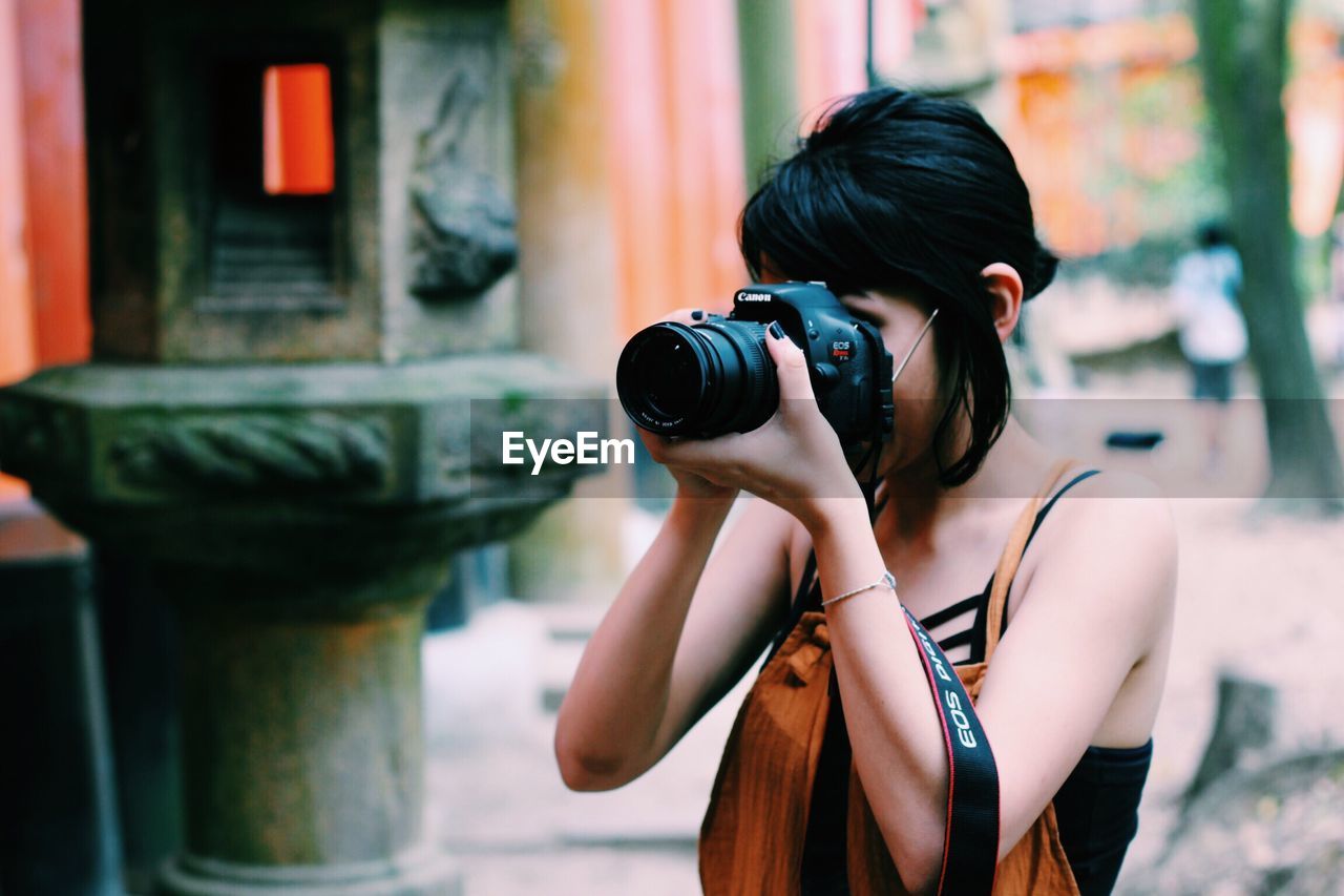 YOUNG WOMAN PHOTOGRAPHING CAMERA