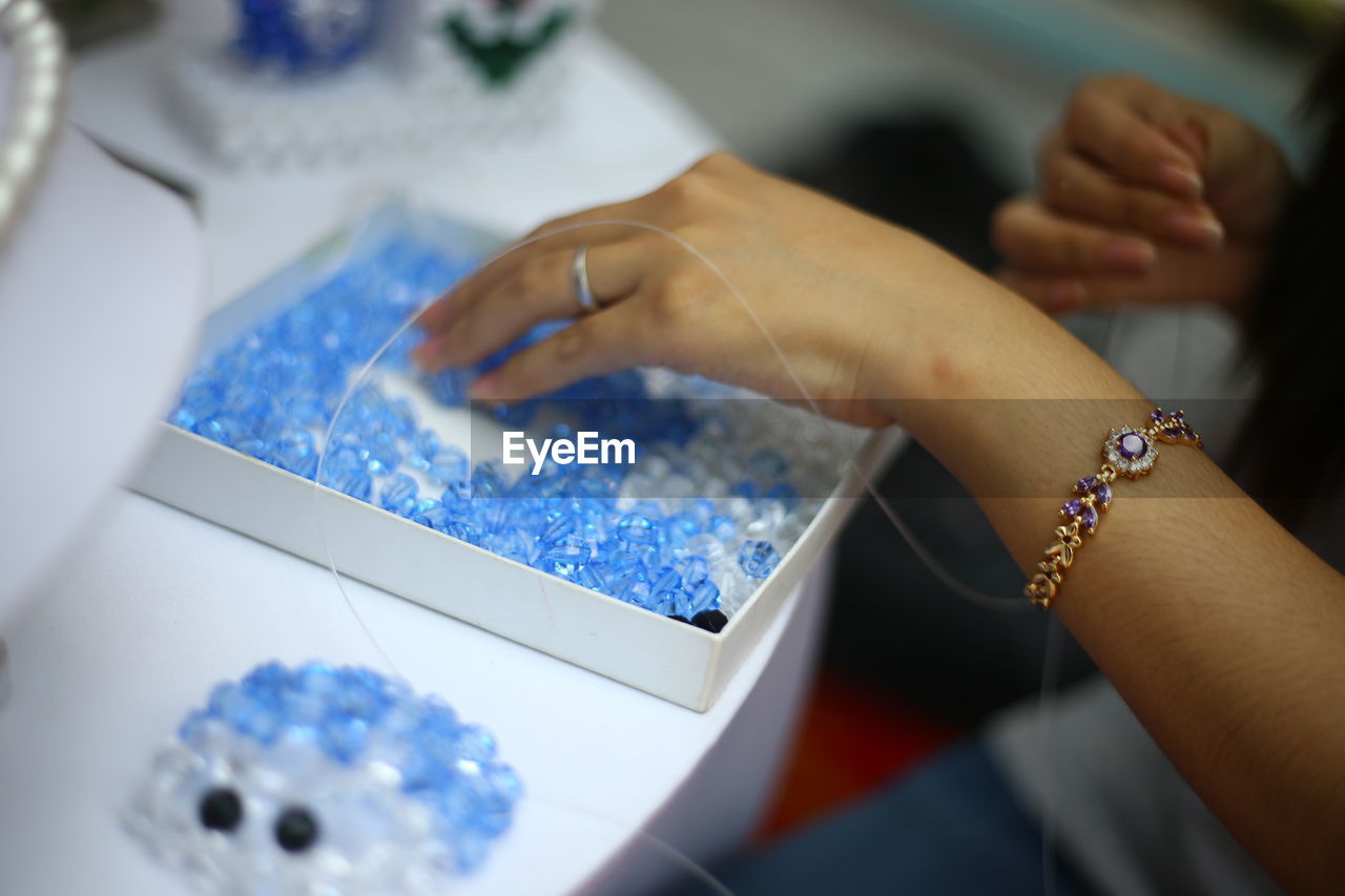 Cropped image of woman working on beads at table