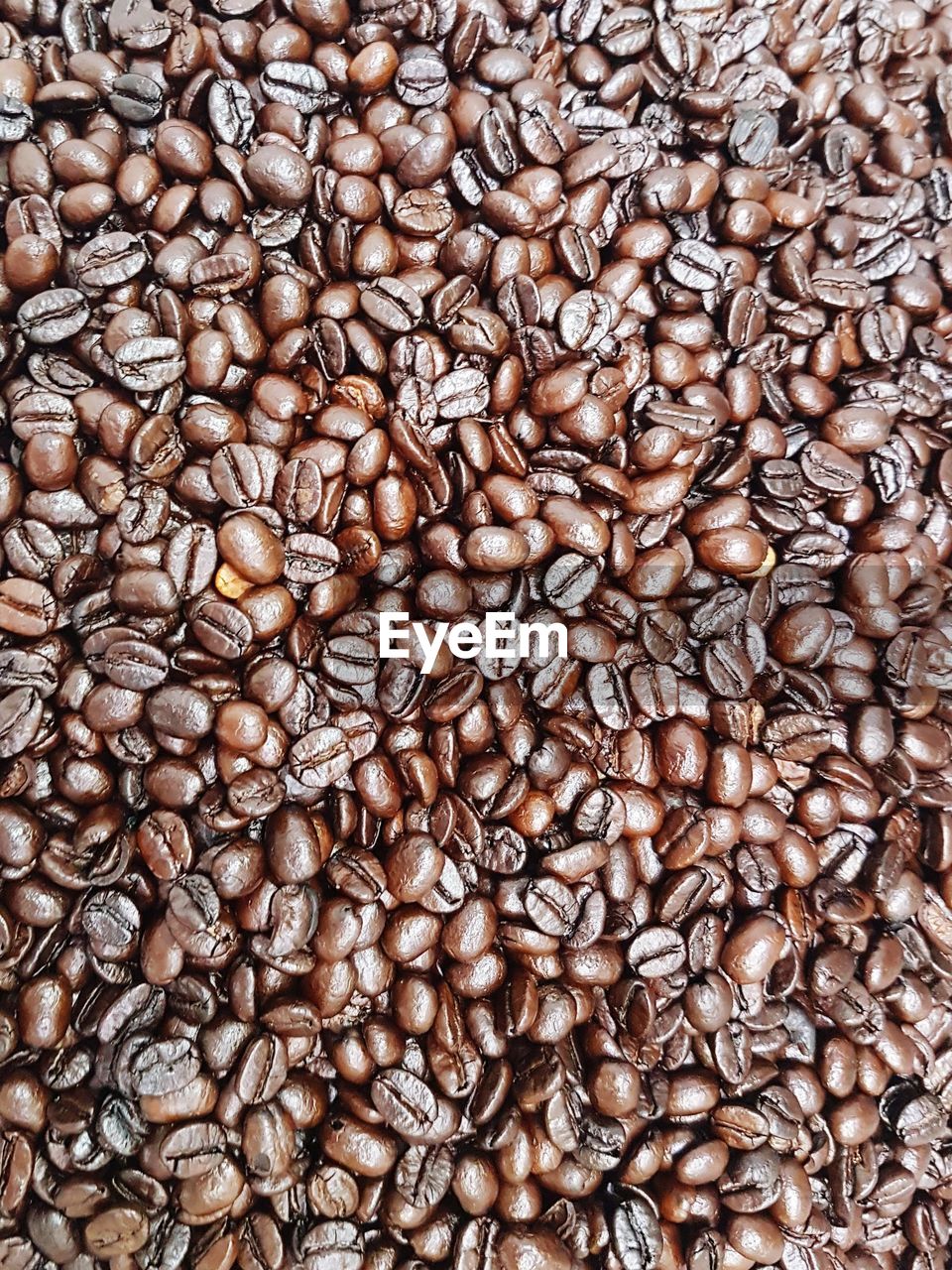 FULL FRAME SHOT OF ROASTED COFFEE BEANS IN BACKGROUND