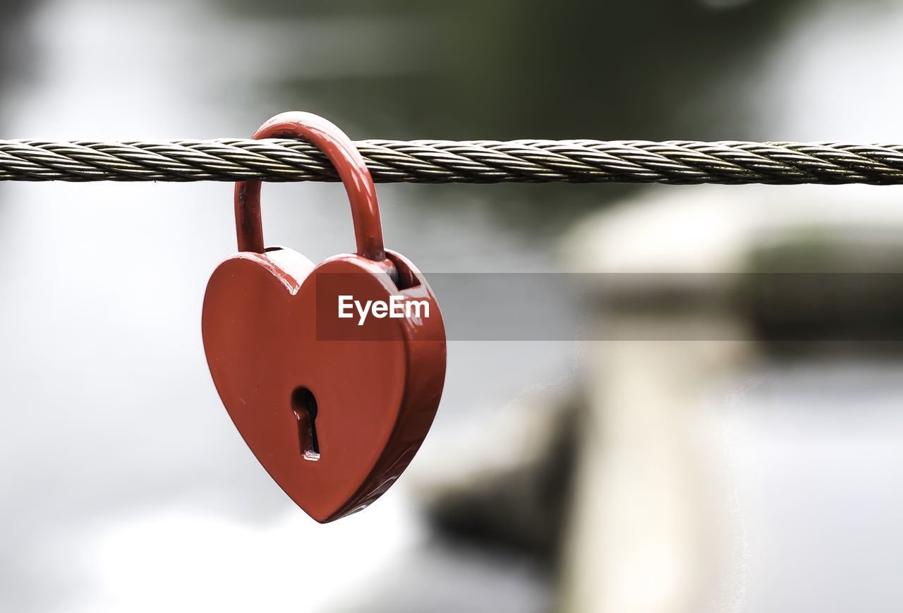 Close-up of heart shape love lock hanging on rope