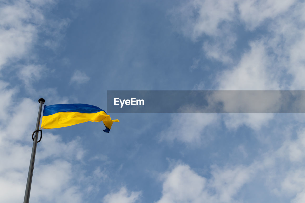 sky, blue, cloud, flag, wind, nature, low angle view, yellow, environment, day, flying, outdoors, patriotism, no people