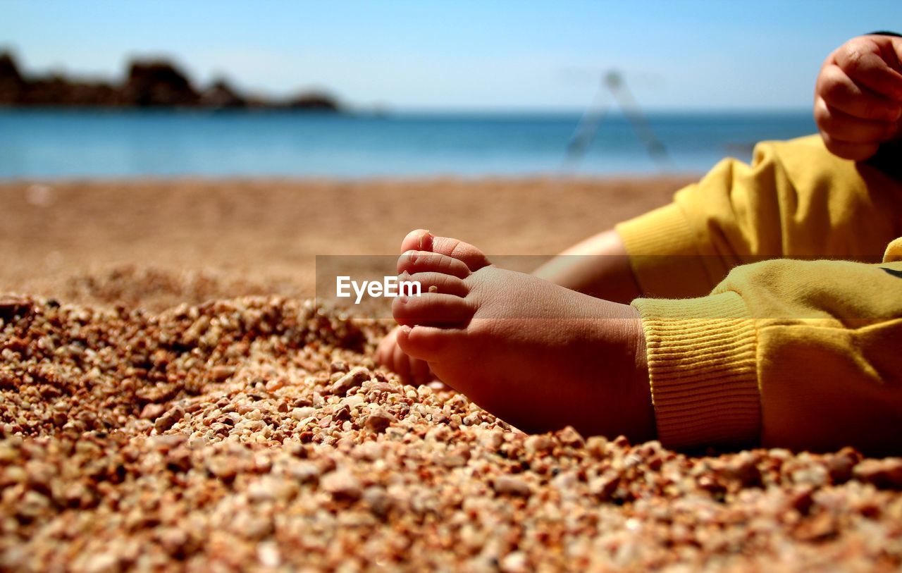 Low section of woman on sand at beach