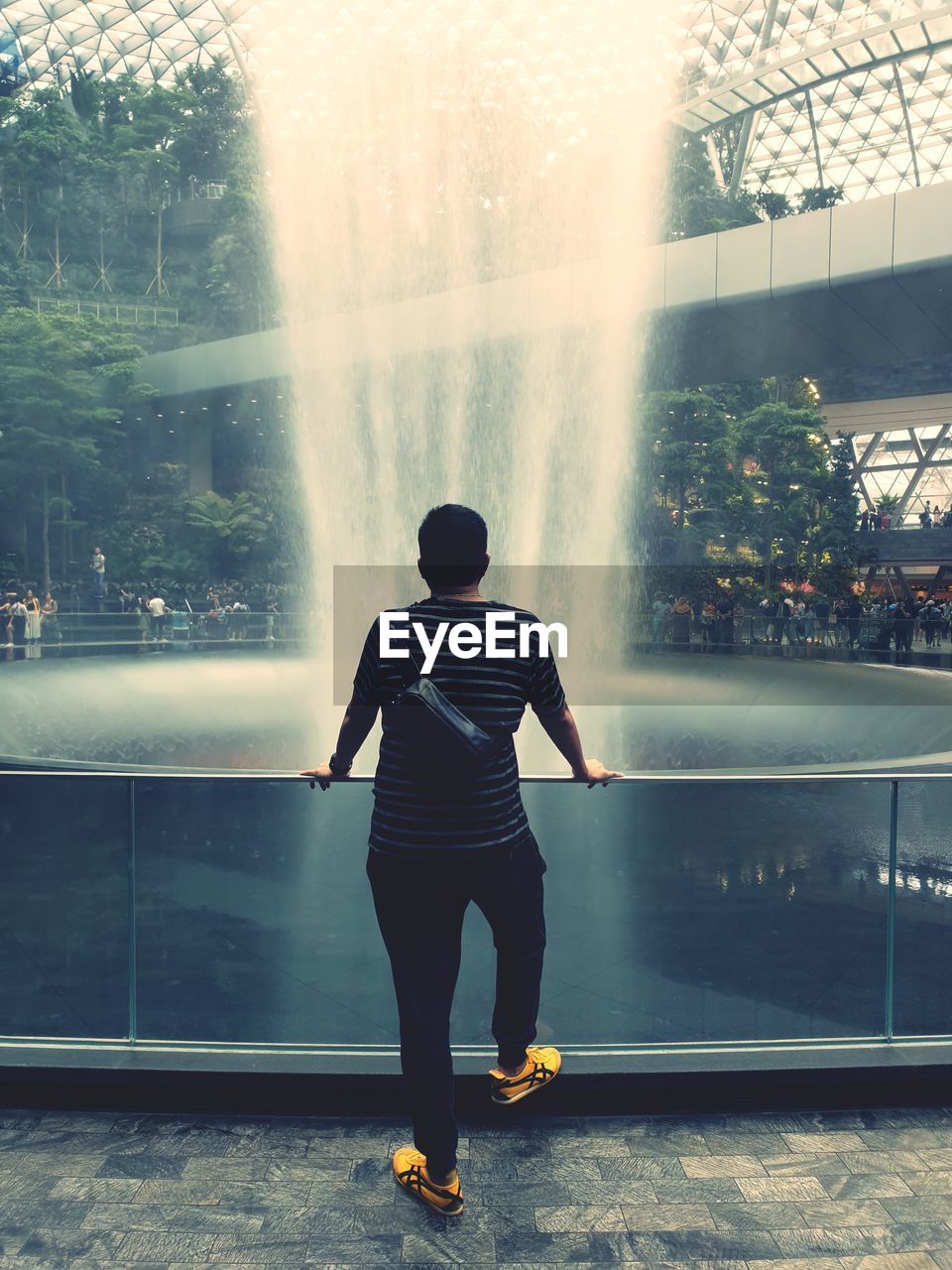 REAR VIEW OF MAN LOOKING AT WATERFALL IN PARK