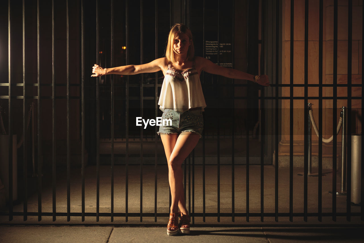 Young woman standing against gate