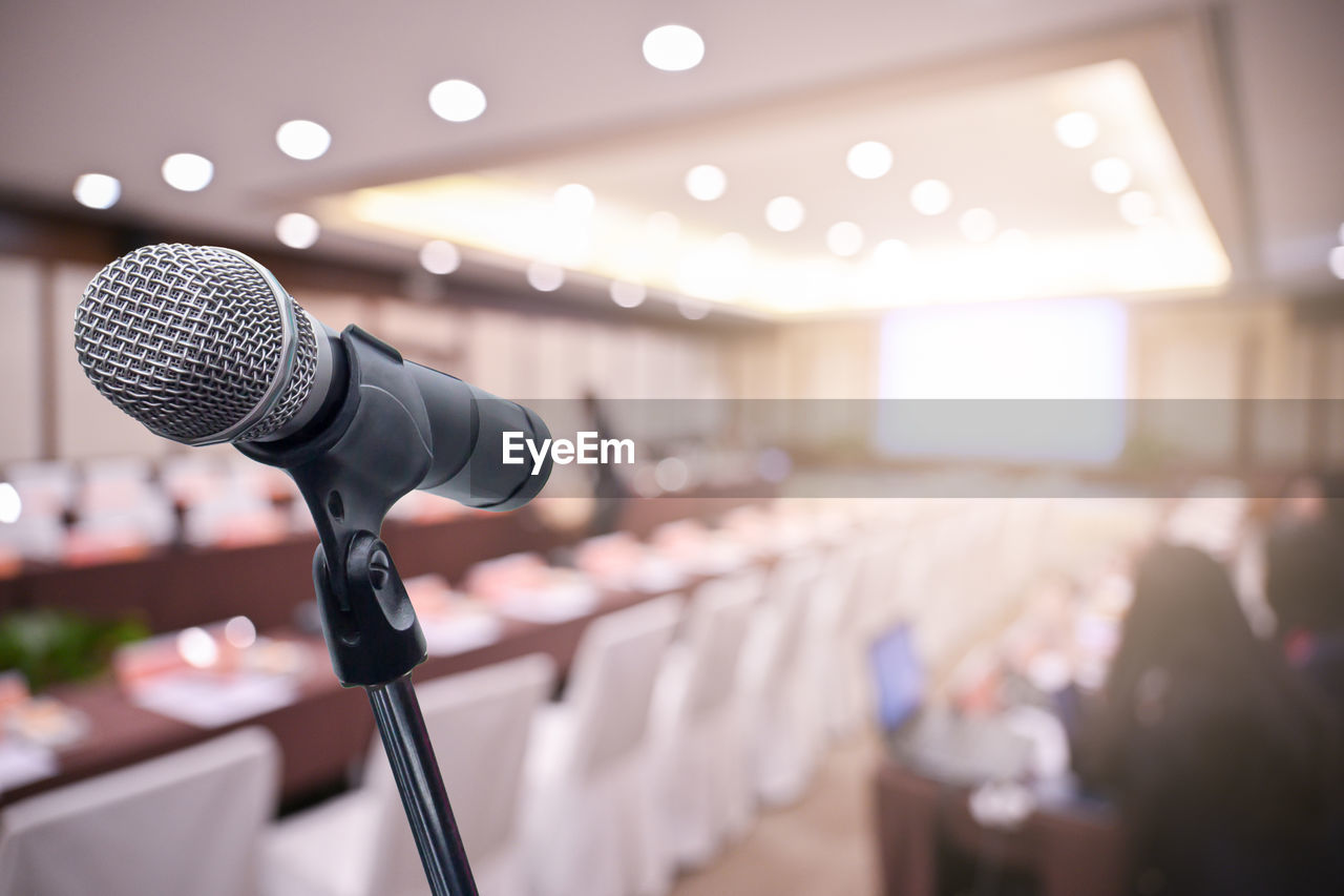 Close-up of microphone against blurred conference hall