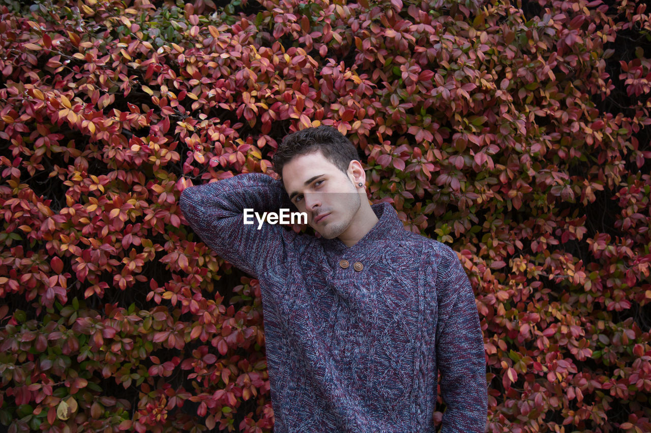 Portrait of handsome man wearing warm clothing while standing against plants