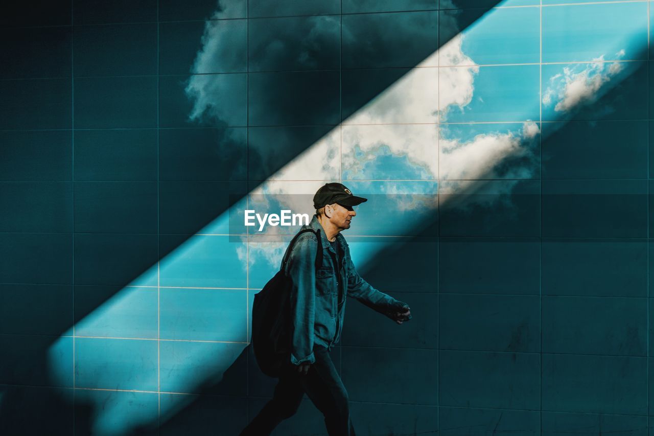 Side view of man walking by wall