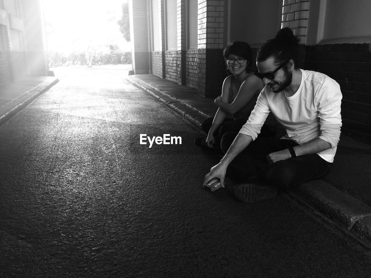 Full length of couple sitting on street curb