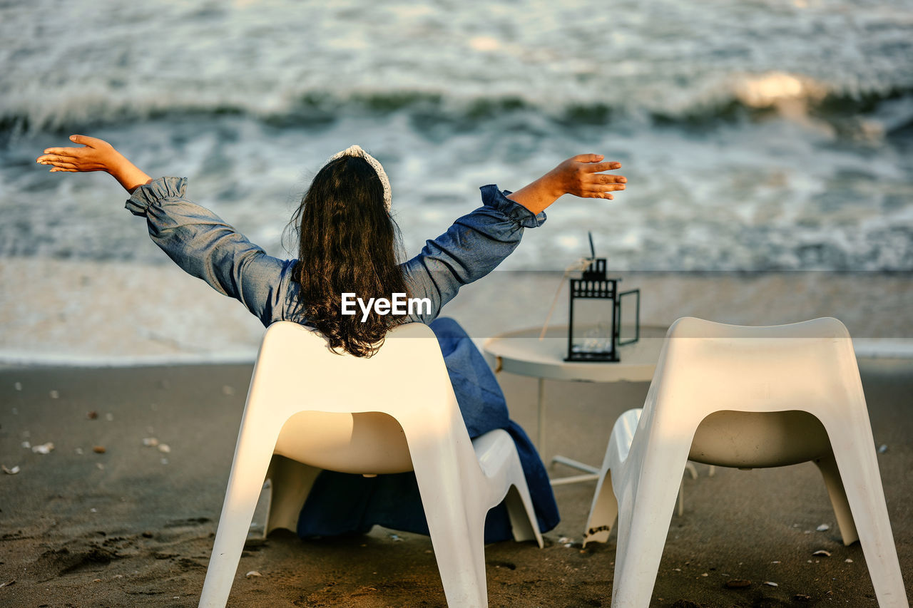 Rear view of woman sitting on beach