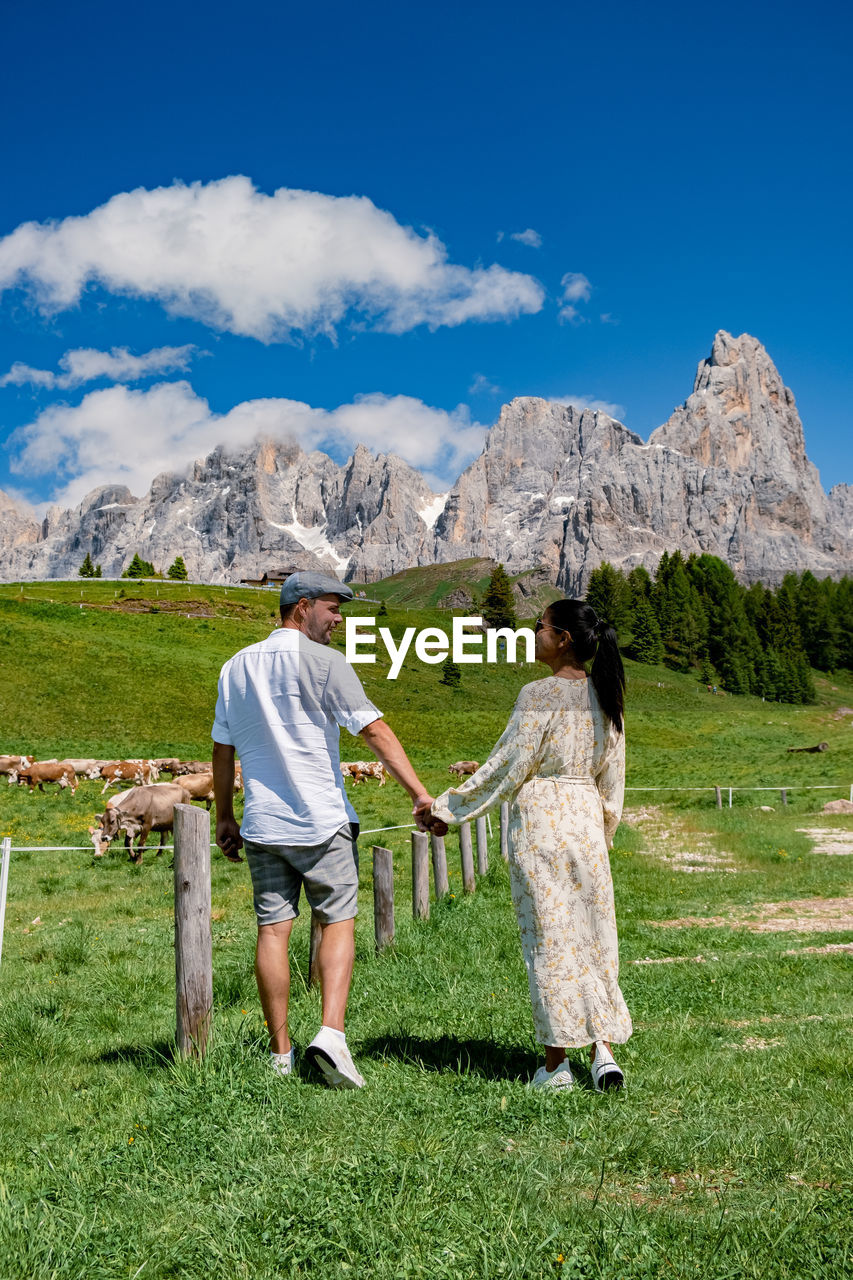 REAR VIEW OF WOMEN STANDING ON LANDSCAPE AGAINST MOUNTAINS