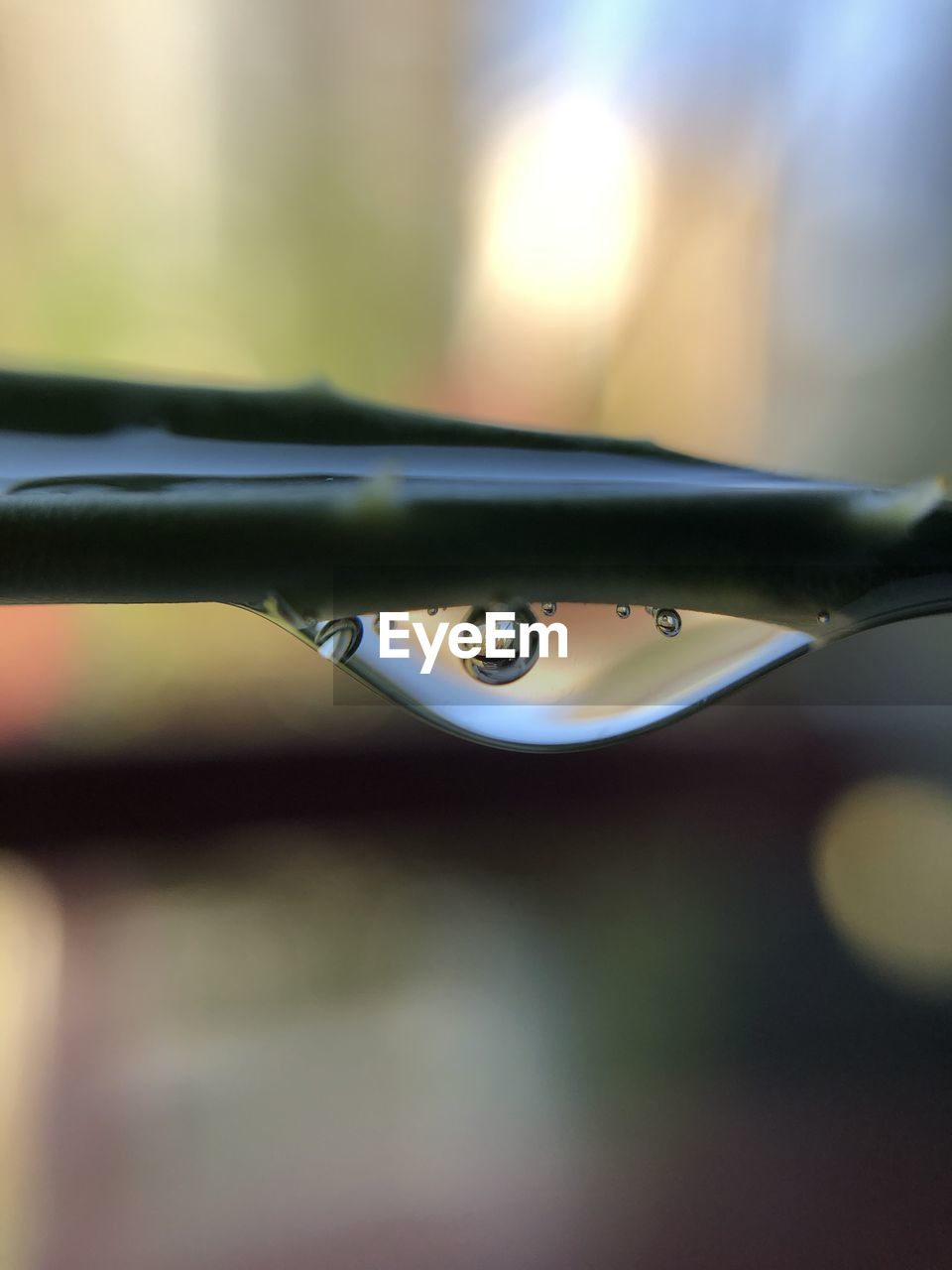 CLOSE-UP OF WATER DROP FALLING FROM METAL