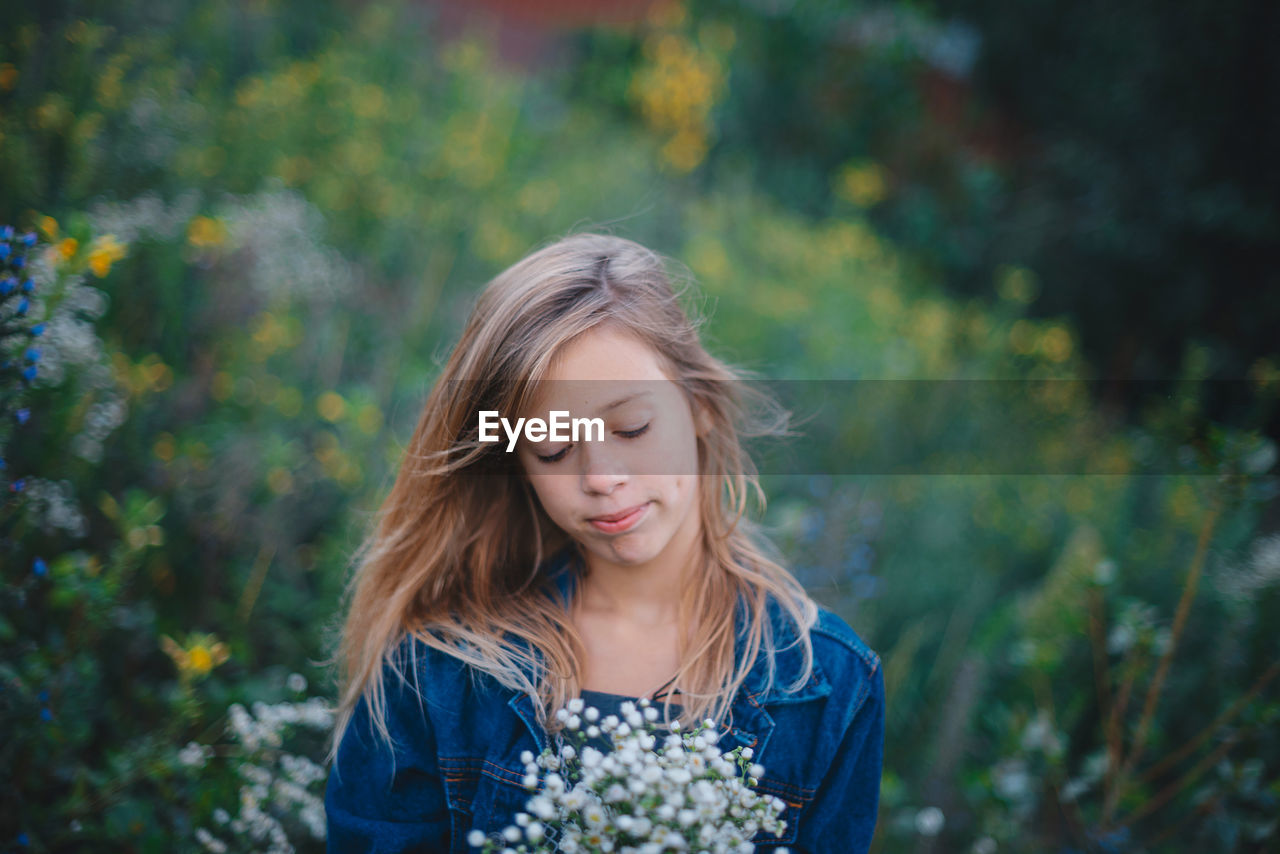 Portrait of young woman standing against plants