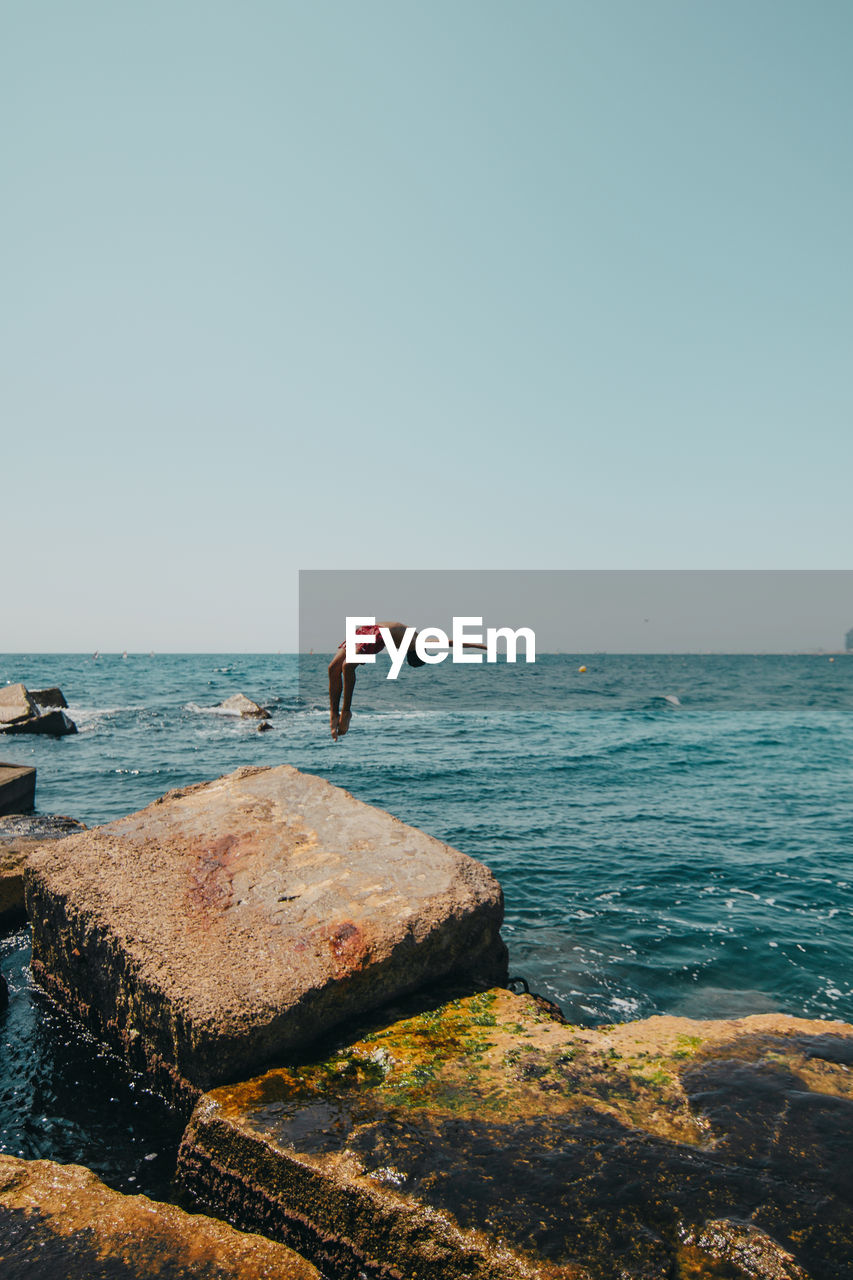 Full length of teenage boy diving in sea against sky