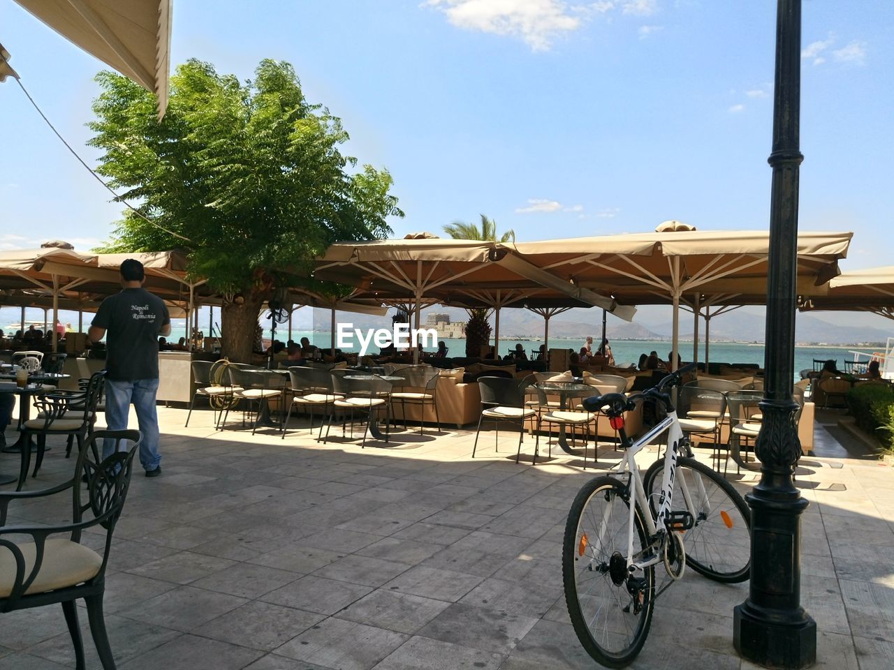 Bicycle parked by pole at sidewalk cafe