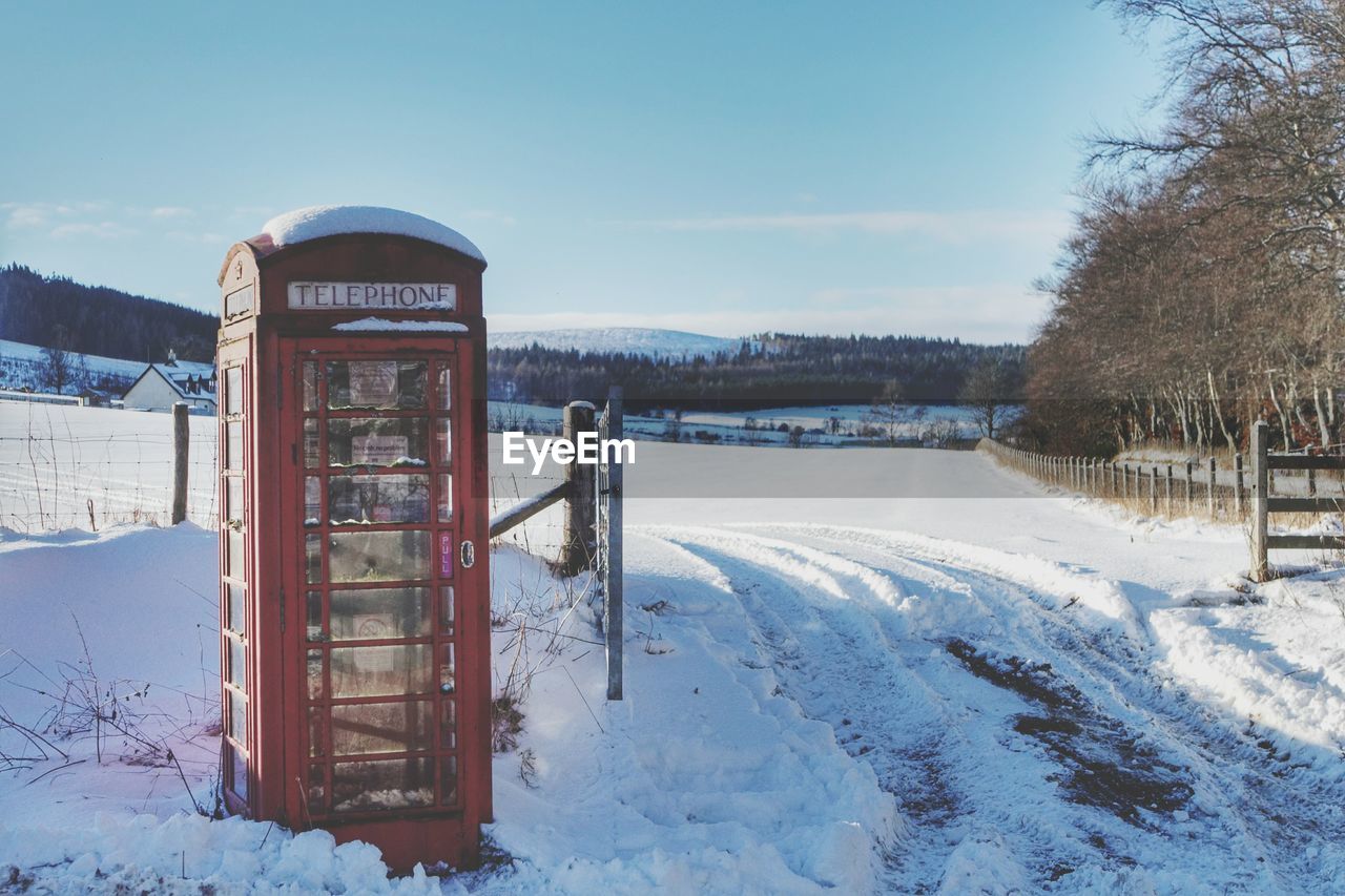 Telephone booth on snow covered landscape in winter