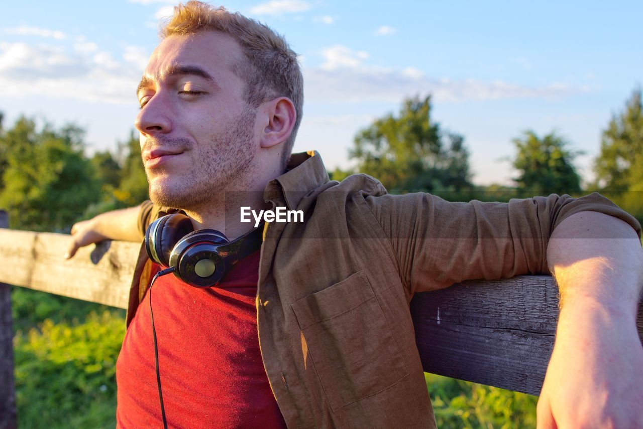 PORTRAIT OF YOUNG MAN LOOKING AWAY OUTDOORS