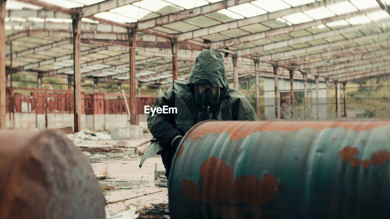 Man with gas mask near radioactive barrels